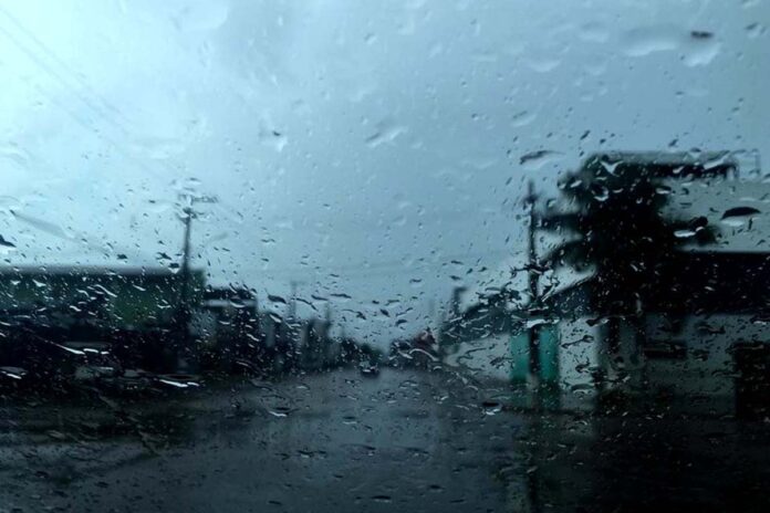 Chuva no para-brisa de carro em dia nublado na Região Norte Visão através do para-brisa de um carro coberto por gotas de chuva, mostrando uma rua da cidade durante um dia de tempo fechado e nublado.