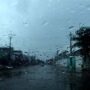 Chuvas atingem a Região Norte, mas o calor continua acima dos 35°C Visão através do para-brisa de um carro coberto por gotas de chuva, mostrando uma rua da cidade durante um dia de tempo fechado e nublado.