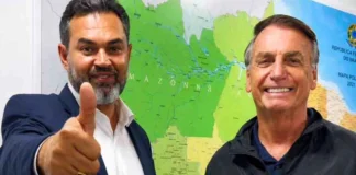 O candidato Bruno Scheid e o ex-presidente Jair Bolsonaro posam juntos para fotografia, estando um mapa do Brasil em pano de fundo.
