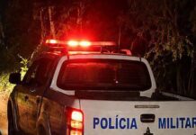 Área externa de um estabelecimento comercial com um homem caído no chão a receber assistência após uma ocorrência policial.