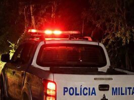 Área externa de um estabelecimento comercial com um homem caído no chão a receber assistência após uma ocorrência policial.