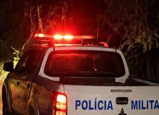 Área externa de um estabelecimento comercial com um homem caído no chão a receber assistência após uma ocorrência policial.