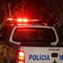 Área externa de um estabelecimento comercial com um homem caído no chão a receber assistência após uma ocorrência policial.