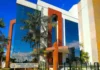 TCE-RO suspende licitação de R$ 1 milhão por restrições Fachada do prédio do Tribunal de Contas do Estado de Rondônia (TCE-RO), com arquitetura moderna, vidros espelhados azuis e detalhes em cor de madeira, cercado por palmeiras sob um céu azul.