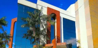 TCE-RO suspende licitação de R$ 1 milhão por restrições Fachada do prédio do Tribunal de Contas do Estado de Rondônia (TCE-RO), com arquitetura moderna, vidros espelhados azuis e detalhes em cor de madeira, cercado por palmeiras sob um céu azul.