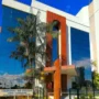 TCE-RO suspende licitação de R$ 1 milhão por restrições Fachada do prédio do Tribunal de Contas do Estado de Rondônia (TCE-RO), com arquitetura moderna, vidros espelhados azuis e detalhes em cor de madeira, cercado por palmeiras sob um céu azul.