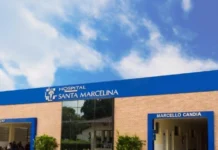 Hospital Santa Marcelina realiza 2ª Feijoada Solidária Fotografia da fachada do Hospital Santa Marcelina, destacando o prédio de tijolos aparentes com letreiro azul e branco e a entrada do setor Marcello Candia, sob um céu claro com nuvens.