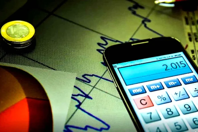 Cálculos da Taxa Selic e Inflação Máquina de calcular digital sobre gráficos financeiros, ilustrando os cálculos económicos do mercado.
