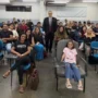 MPRO debate consumo consciente com acadêmicos de Direito O promotor de Justiça Alan Castiel Barbosa, de terno e gravata, posa sorridente em pé no fundo de uma sala de aula universitária, acompanhado por dezenas de estudantes de Direito acomodados em cadeiras azuis.