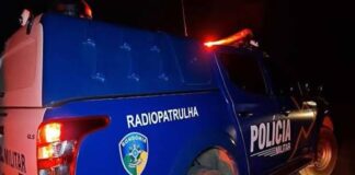 Fotografia noturna da lateral de uma carrinha de patrulha da Polícia Militar de Rondônia, com as luzes traseiras acesas.