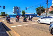 Acidentes com motos ampliam demanda do SAMU em PVH Trânsito em Porto Velho, mostrando vários motociclistas e um carro branco parados aguardando o semáforo abrir em um dia ensolarado.