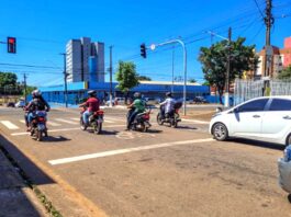 Acidentes com motos ampliam demanda do SAMU em PVH Trânsito em Porto Velho, mostrando vários motociclistas e um carro branco parados aguardando o semáforo abrir em um dia ensolarado.
