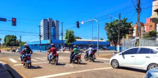 Acidentes com motos ampliam demanda do SAMU em PVH Trânsito em Porto Velho, mostrando vários motociclistas e um carro branco parados aguardando o semáforo abrir em um dia ensolarado.