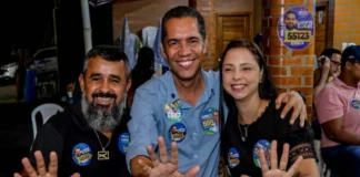 O candidato ao Senado, Luis Fernando, veste camisa azul e sorri para a foto ao lado de dois apoiadores, todos com as mãos abertas indicando o número 55.