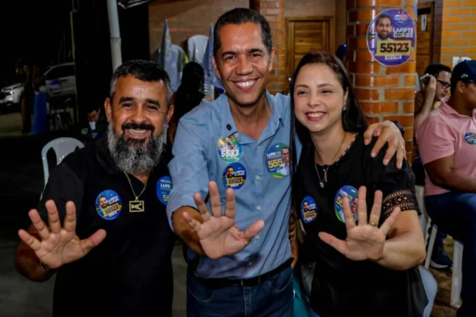 O candidato ao Senado, Luis Fernando, veste camisa azul e sorri para a foto ao lado de dois apoiadores, todos com as mãos abertas indicando o número 55.