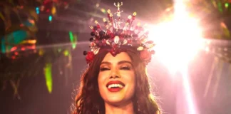 Anitta coroada rainha de bateria da Grande Rio A cantora Anitta sorridente e iluminada, a usar uma coroa vermelha cravejada de pedras e búzios durante o evento da Grande Rio.