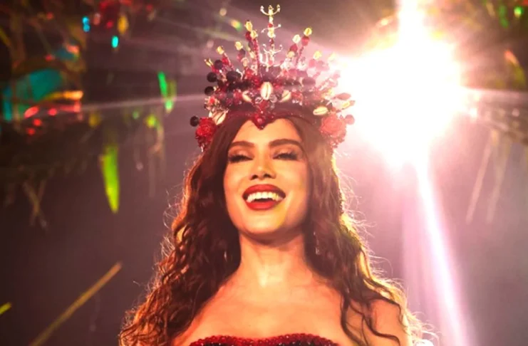 Anitta coroada rainha de bateria da Grande Rio A cantora Anitta sorridente e iluminada, a usar uma coroa vermelha cravejada de pedras e búzios durante o evento da Grande Rio.