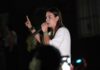 Mariana defende fronteira mais protegida para quem vive em Rondônia Mariana Carvalho, candidata ao Senado, segura um microfone e discursa para o público durante um evento noturno de campanha.