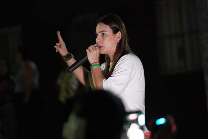Mariana Carvalho discursa sobre segurança nas fronteiras de Rondônia Mariana Carvalho, candidata ao Senado, segura um microfone e discursa para o público durante um evento noturno de campanha.