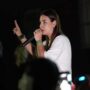 Mariana defende fronteira mais protegida para quem vive em Rondônia Mariana Carvalho, candidata ao Senado, segura um microfone e discursa para o público durante um evento noturno de campanha.
