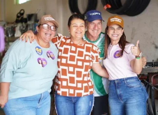 “Onda 100” de Mariana Carvalho cresce no interior de RO Mariana Carvalho, usando boné e camisa de campanha, sorri e abraça calorosamente três apoiadores durante um evento eleitoral no interior de Rondônia.