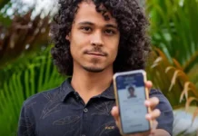 Prazo para baixar o e-Título termina no dia 3 de outubro Um jovem de cabelos cacheados sorri levemente enquanto exibe, em primeiro plano, a tela do seu celular com o aplicativo do e-Título aberto e validado.