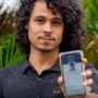 Prazo para baixar o e-Título termina no dia 3 de outubro Um jovem de cabelos cacheados sorri levemente enquanto exibe, em primeiro plano, a tela do seu celular com o aplicativo do e-Título aberto e validado.