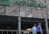 Fachada do edifício sede da Petrobras com portões metálicos e pessoas a caminhar na entrada.