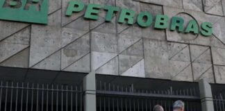 Petrobras aprova adesão à subvenção para o óleo diesel Fachada do edifício sede da Petrobras com portões metálicos e pessoas a caminhar na entrada.