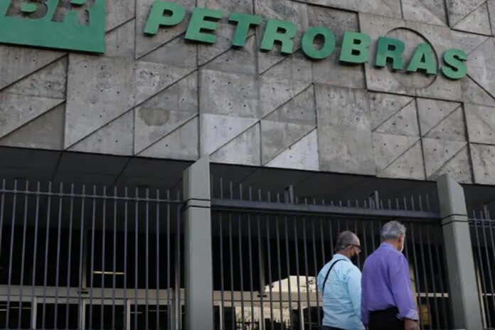 Fachada da sede da Petrobras Fachada do edifício sede da Petrobras com portões metálicos e pessoas a caminhar na entrada.