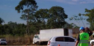 TJRO trava recurso da Nova 364 sobre buraco em rodovia Funcionário com colete da Nova 364 a sinalizar a rodovia junto a barreiras de segurança e veículos em trânsito.