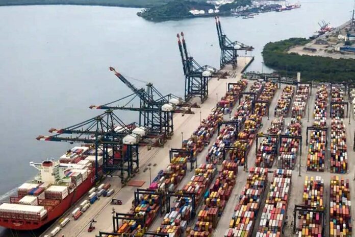Porto Comercial Brasileiro em Atividade Vista aérea de um porto comercial repleto de contentores de carga, simbolizando o movimento da economia brasileira.