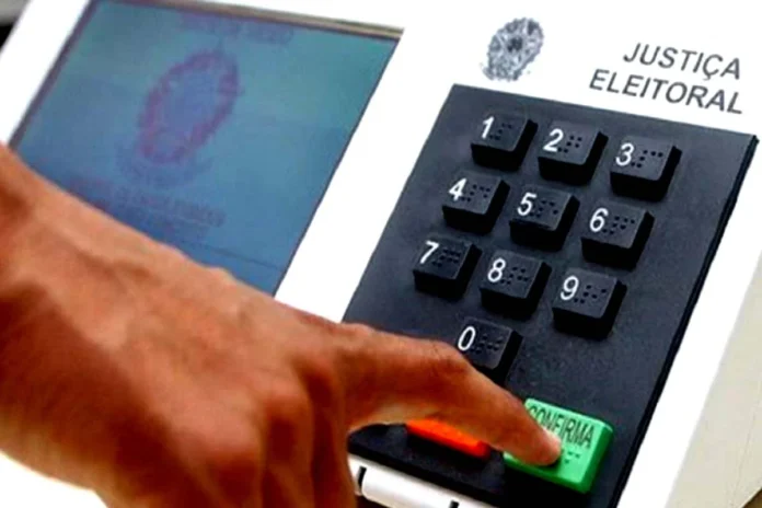 urna eleitoral Dedo de um eleitor a pressionar a tecla verde de confirmação numa urna eletrónica da Justiça Eleitoral.