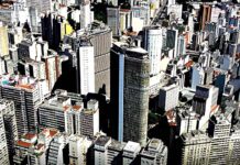 Fotografia aérea de uma cidade com grandes edifícios, representando a densidade e o desenvolvimento urbano.