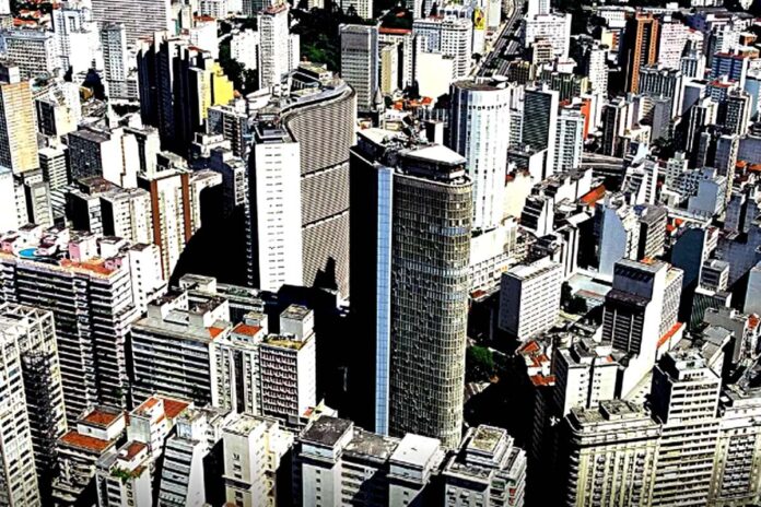 @ Fotografia aérea de uma cidade com grandes edifícios, representando a densidade e o desenvolvimento urbano.