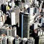 Fotografia aérea de uma cidade com grandes edifícios, representando a densidade e o desenvolvimento urbano.