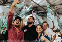 Os candidatos Jean Oliveira e Márcia Oliveira sorriem e celebram com apoiadores durante uma grande reunião política em Porto Velho.