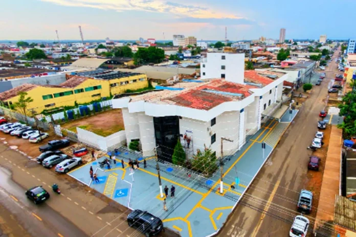 Fotografia aérea mostrando a fachada e a infraestrutura do novo Hospital Municipal de Porto Velho, um prédio amplo e pintado de branco, com movimentação na rua ao redor.