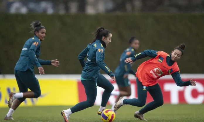 Jogadoras da seleção brasileira feminina em treinamento Jogadoras da seleção brasileira feminina durante um treinamento no gramado, vestindo uniformes azuis e laranjas com o escudo da CBF.