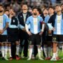 O jogador Lionel Messi em pé no gramado do estádio, olhando para o alto com uma expressão de claro desconforto e frustração.