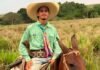 Jovem de 20 anos morre afogado após cair de barco durante pescaria no Rio Machado Fotografia do jovem Marcos André Ferreira Santos montado a cavalo, sorrindo e vestindo um chapéu de palha, camisa verde e lenço colorido no pescoço em uma área de pastagem.