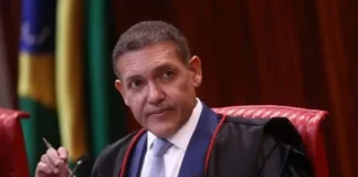 TSE determina suspensão de canal de André Janones no WhatsApp a pedido de Flávio Bolsonaro O ministro Kassio Nunes Marques, presidente do TSE, vestindo toga preta e gravata azul, segurando uma caneta durante uma sessão no tribunal.