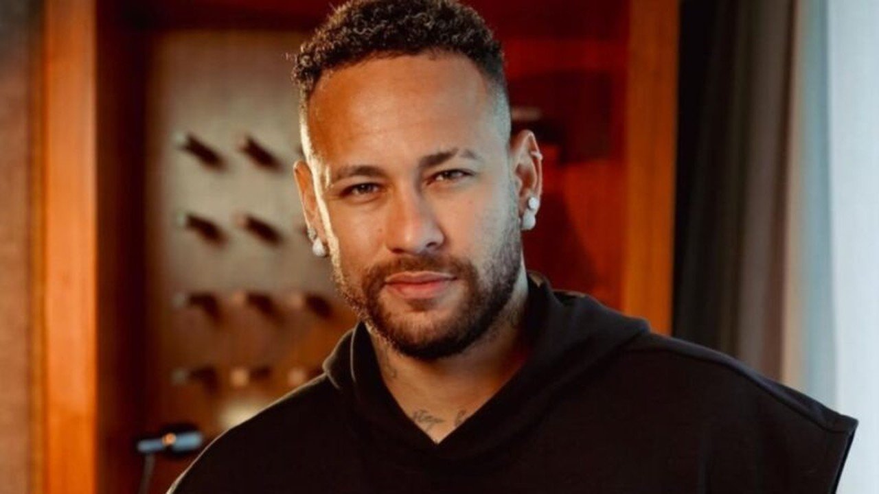 Neymar Jr de perto, olhando para a câmera, com barba, cabelo crespo e camiseta preta