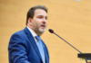 Deputado Alex Redano agradece apoio nas urnas e renova compromissos sociais O deputado estadual Alex Redano a discursar num púlpito ao microfone, envergando um fato azul-escuro e gravata azul-clara.