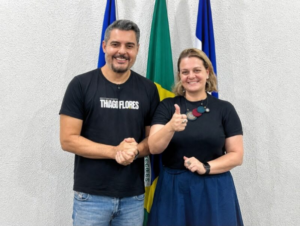 Vereadora Amanda Areval e deputado federal reeleito Thiago Flores A vereadora Amanda Areval e o deputado federal Thiago Flores posam lado a lado sorrindo durante um evento político, vestindo camisas de campanha.