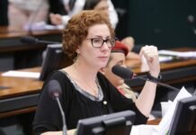 A ex-deputada federal Carla Zambelli, vestindo trajes formais, falando ao microfone durante uma sessão parlamentar.