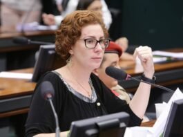 Justiça italiana agenda nova audiência sobre extradição de Carla Zambelli A ex-deputada federal Carla Zambelli, vestindo trajes formais, falando ao microfone durante uma sessão parlamentar.