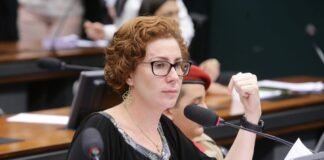 Justiça italiana agenda nova audiência sobre extradição de Carla Zambelli A ex-deputada federal Carla Zambelli, vestindo trajes formais, falando ao microfone durante uma sessão parlamentar.