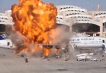 Ataques a aeroportos na Arábia Saudita deixam 12 mortos e mais de 300 feridos Grande explosão com chamas intensas e fumaça atingindo a lateral de um avião comercial de passageiros estacionado na pista de um aeroporto.