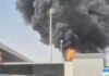 Após ataque fatal, houthis ameaçam espaço aéreo e paralisam voos na Arábia Saudita Densa nuvem de fumaça escura e chamas intensas subindo por trás do muro e da estrutura do terminal de um aeroporto, evidenciando uma forte explosão.